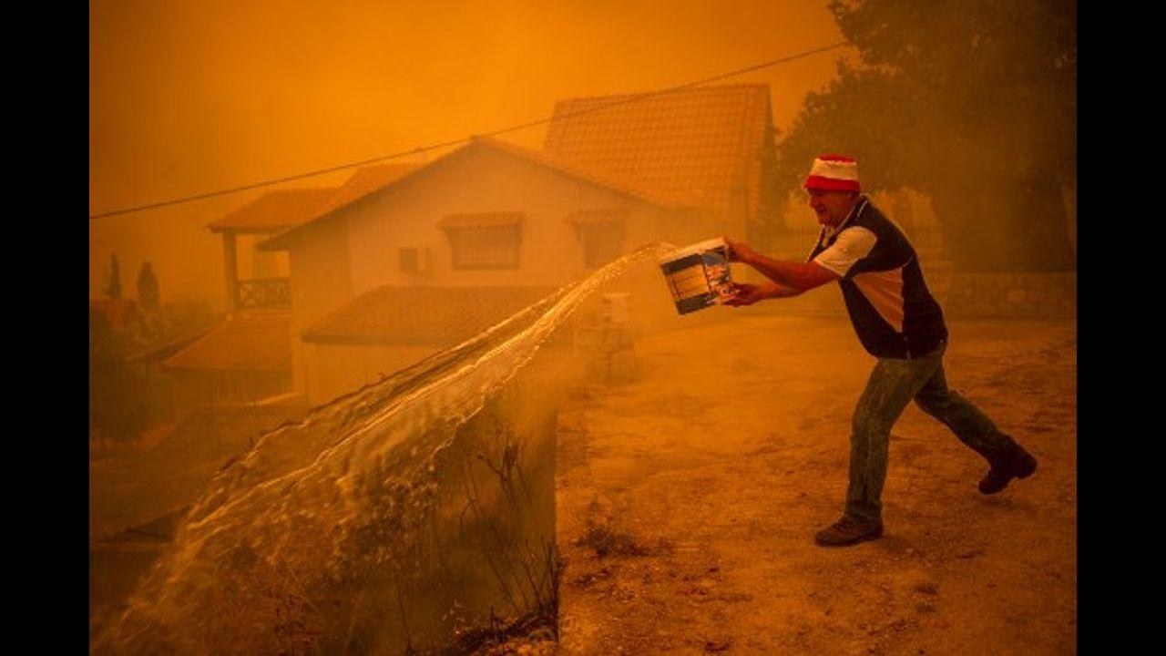 A local resident drops water as he fights the wildfire in the village of Gouves on Evia (Euboea) island, second largest Greek island.